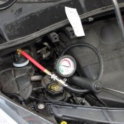 Trycktest av kylsystem med handpump och adapter ansluten till expansionskärl